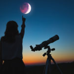 Girl looking at lunar eclipse through a telescope. My astronomy work.