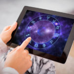 Woman reading horoscopes on tablet